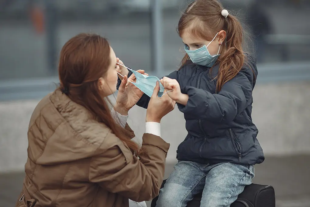 Mother teaching daughter how to wear a surgical mask for emergency preparedness