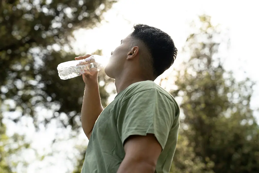 A man is drinking cool water from a bottle to survive the extreme heat and keep his body hydrated