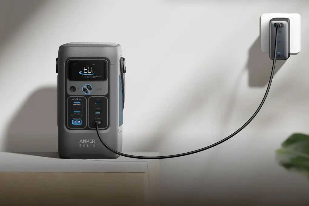 A Anker Solix C200 DC power station sits on a table, charging via a cable plugged into a wall socket